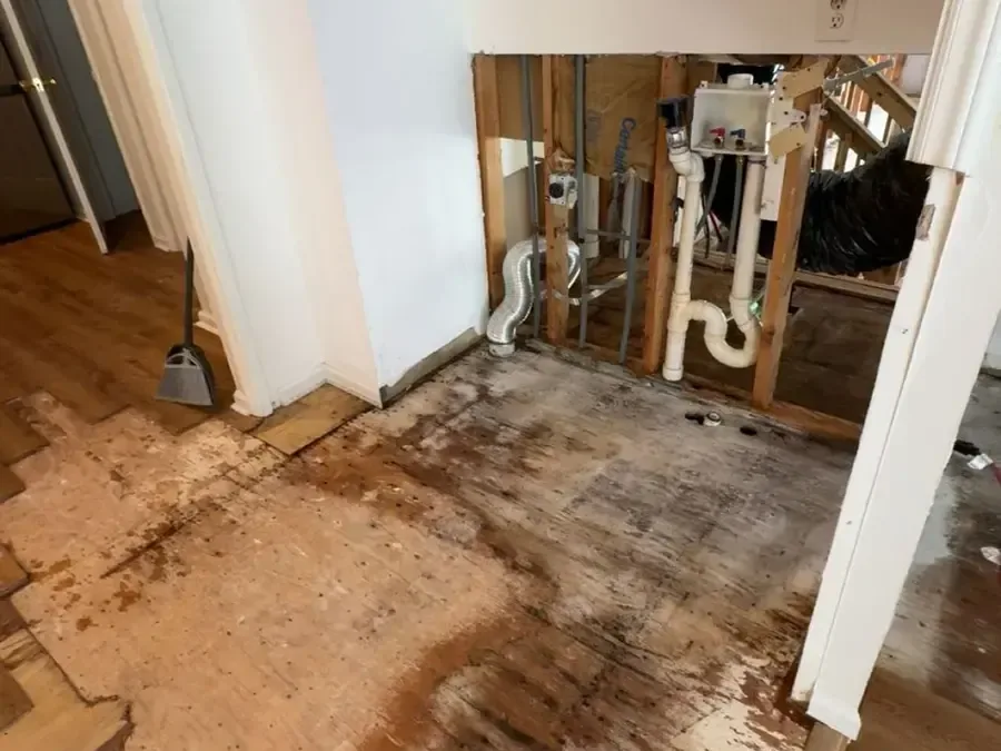 A wall opened around the plumbing with the wet flooring pulled back